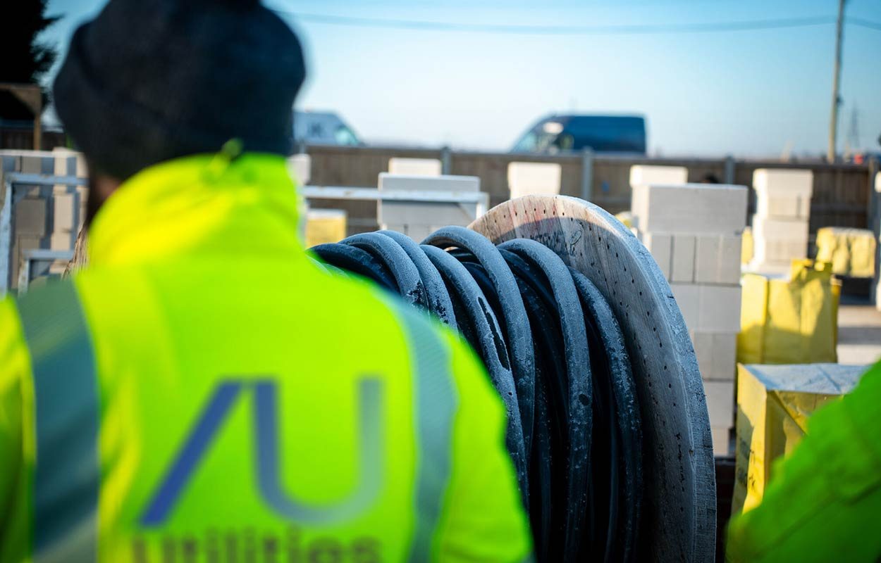 Anglian Utilities consultant beside cable drums on site
